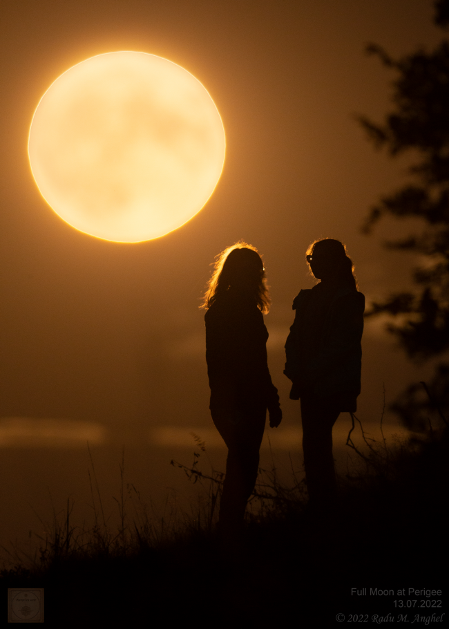 Supermoon: Bright full orangish moon with a woman and a girl watching it. The brightness of the moon shines in their hair.