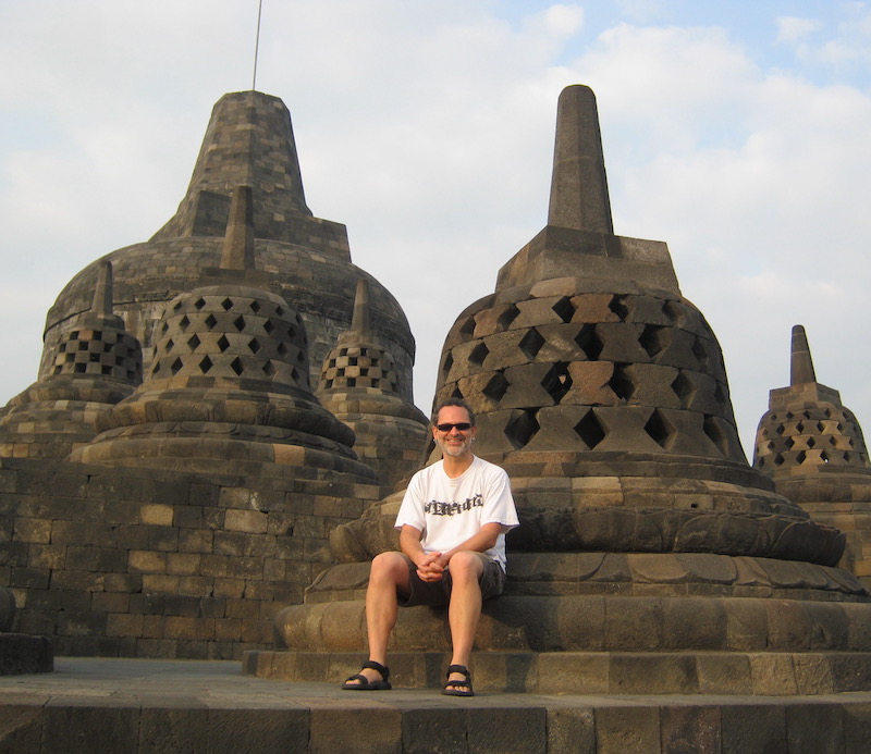 Man sitting in front of spire-like monuments.