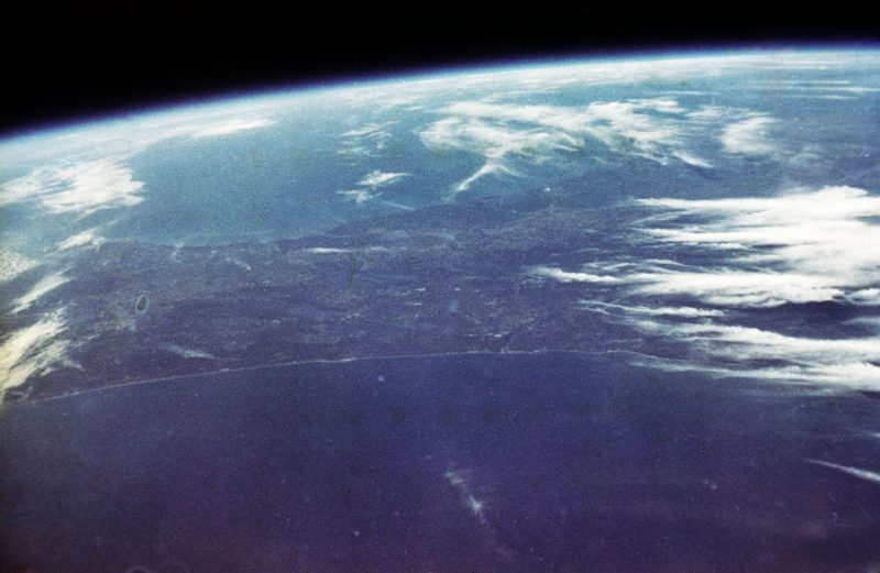 John Glenn's orbital view of Earth, mostly blue sea with some white clouds.