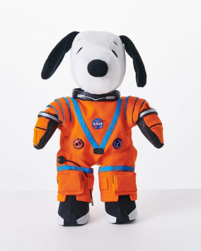 Black and white stuffed toy dog with orange jumpsuit.