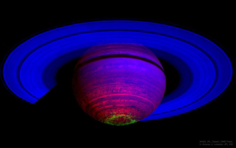 Saturn and its rings in blue and purple, with a thin, irregular green circle around its pole.