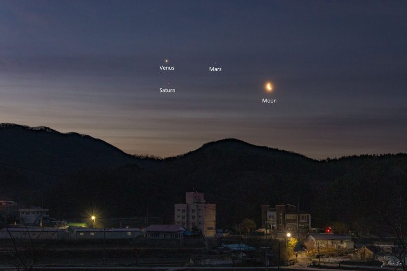 Dawn with a mountain foreground, the moon and three bright planets.