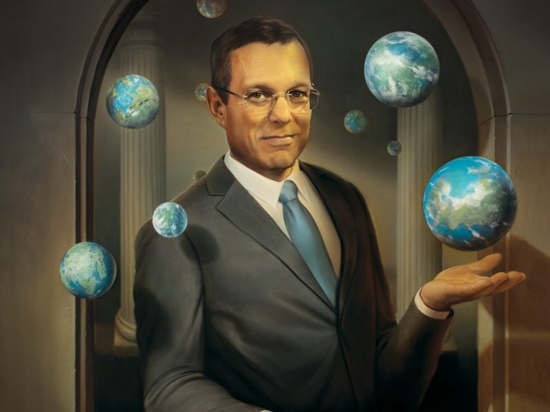 alien artifacts: Man with glasses in suit with hand out and surrounded by floating globes.