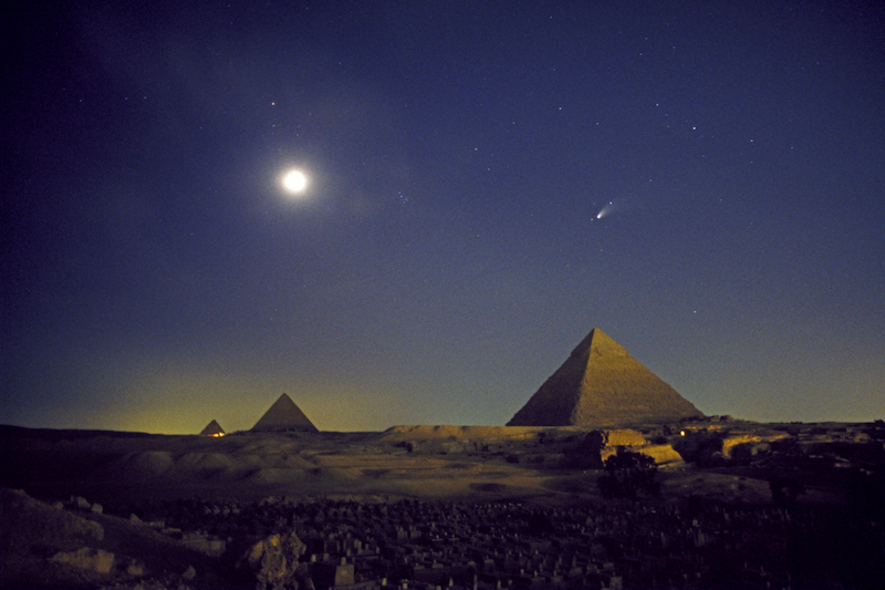 Bright light (saturated moon) and a comet over a landscape with pyramids.