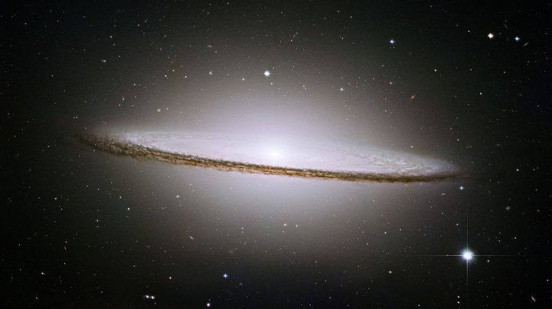 Edge-on galaxy with dark lane of dust and diffuse, bright central area.