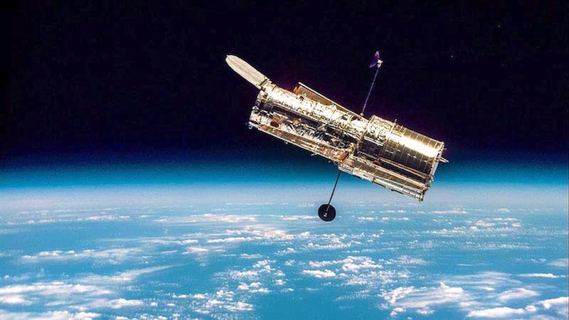 Hubble: Large telescope orbiting above Earth in space.