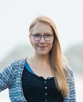 Smiling young woman with long blonde hair on right side and eyeglasses.