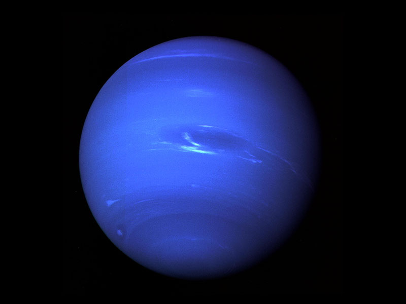 Blue planet with light and dark streaks and clouds in its atmosphere.