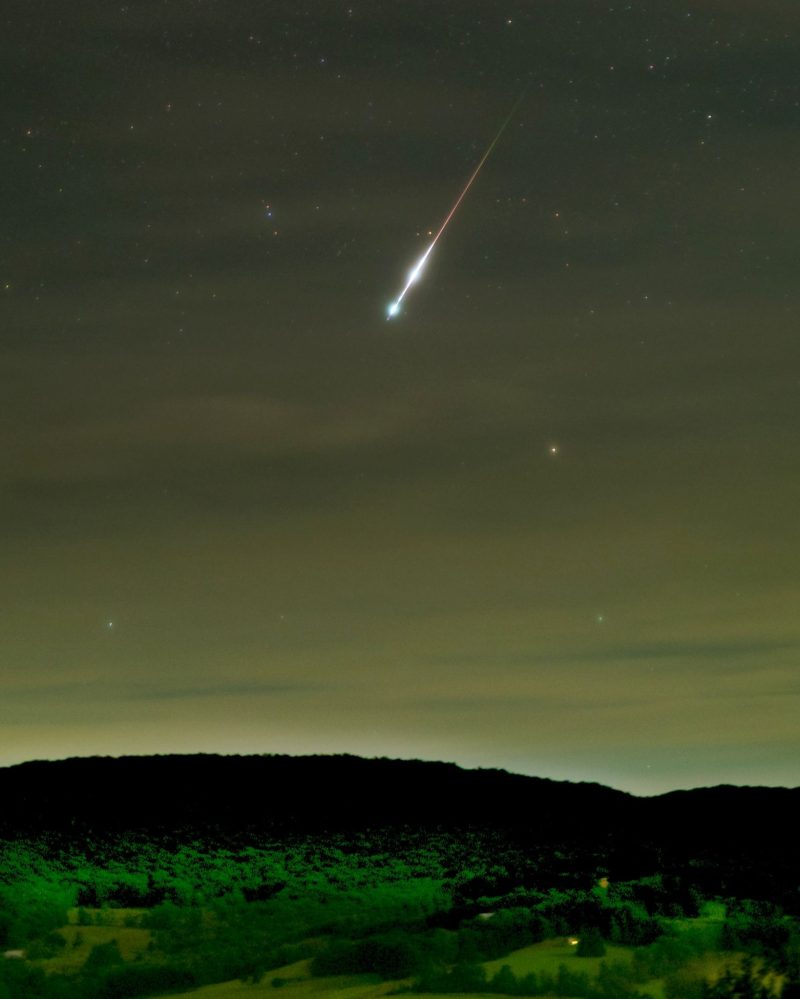 Interstellar meteor: bright meteor in sky above mountains.