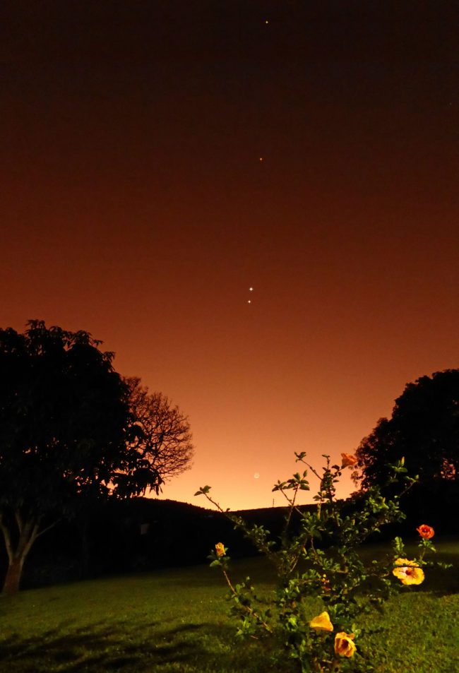 Orange sunrise with line of dots leading up from horizon plus moon at bottom.