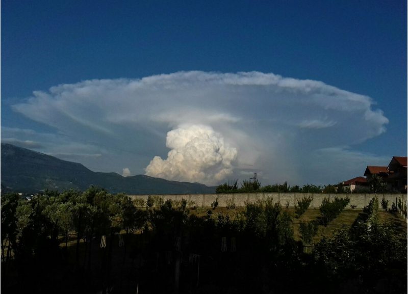 Bright white bubbling cloud with large thinner cloud flat top above it.