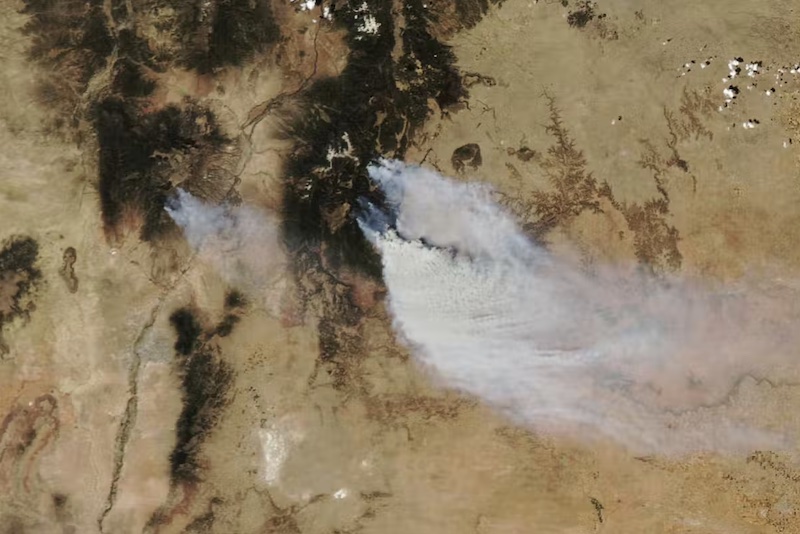 Fire season: Orbital view of brown land with large black areas with smoke streaming from them.