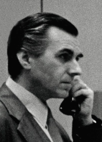 A serious-looking man, talking on the phone.