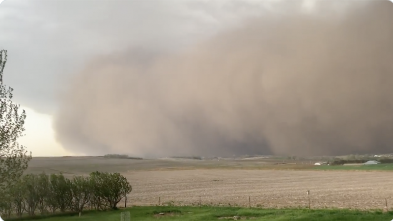 A huge cloud of dust over a farmer's field.