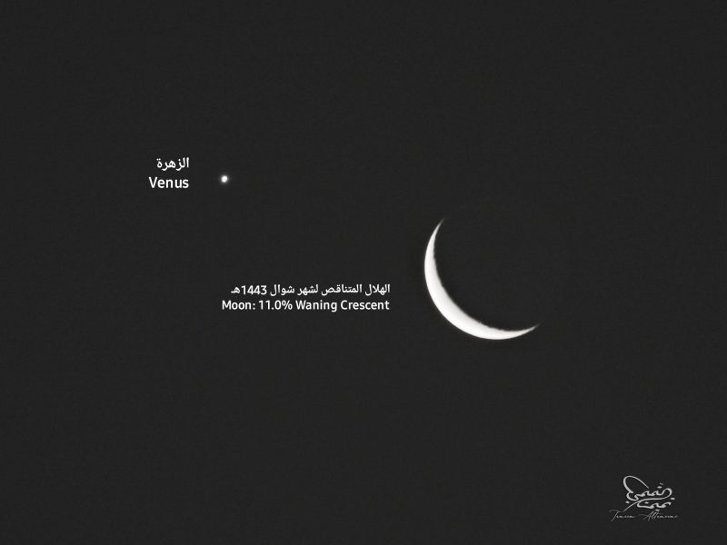 Thin crescent moon labeled in Arabic and English and similarly labeled bright Venus.