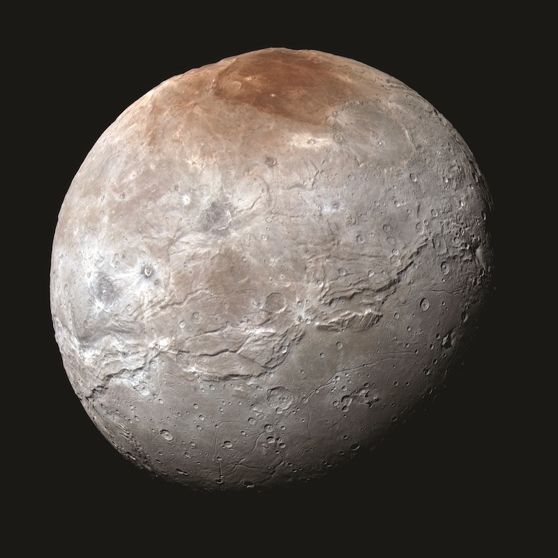 Charon's red cap: gray planet-like body with long valley and reddish polar cap.