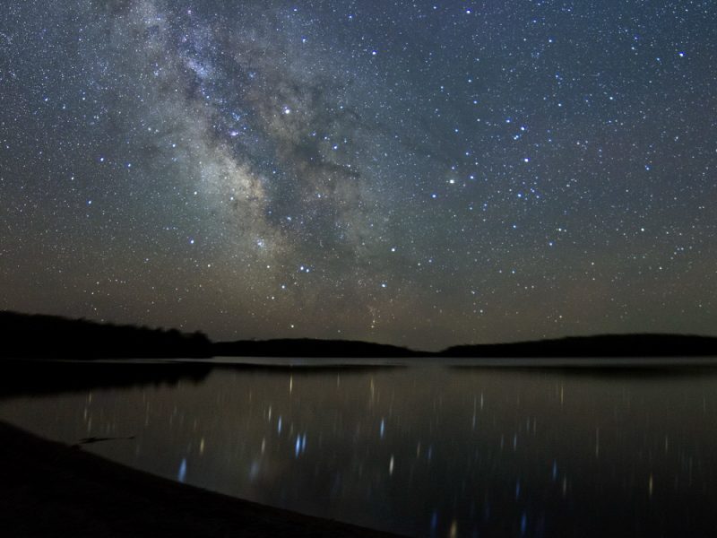 Lake Kejimkujik at night, with stars reflecting in water.