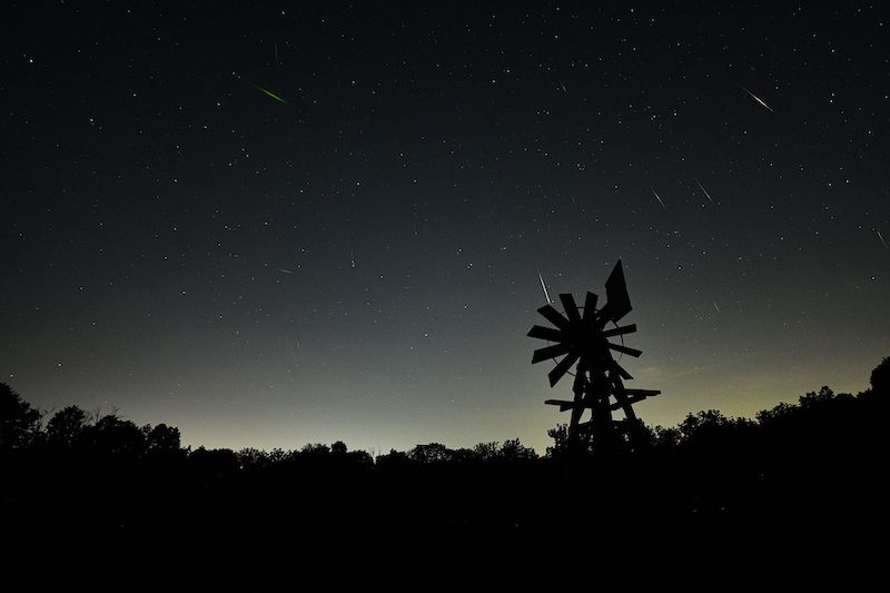 Stars and white meteor streaks against a black background.