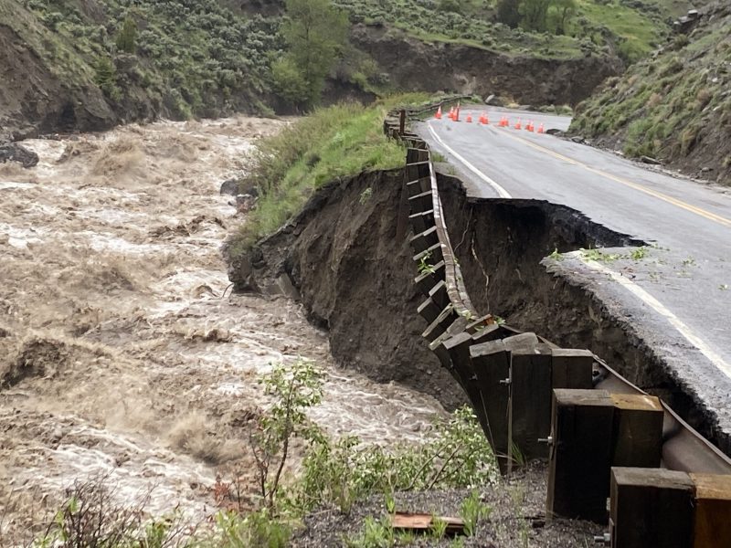 Yellowstone: Roaring river beside road where guardrail is falling and road partially washed out.