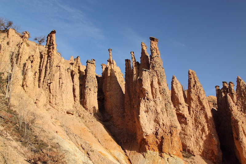 Tall spikes of rock on slope, with blue sky above.