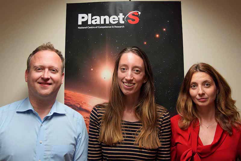 1 man and 2 women, all smiling. standing in front of poster with PlanetS logo.