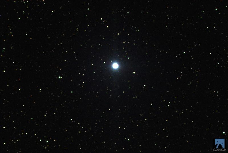 Many stars in a black background. A star in the middle is bigger and shines bright.