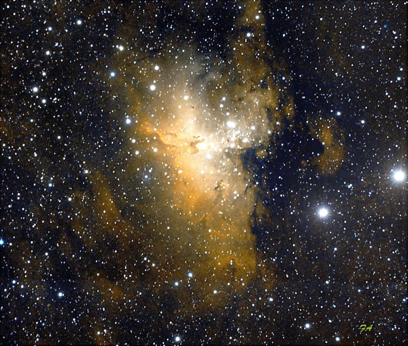 Large cloud of yellow nebulosity behind star field with many bright stars.