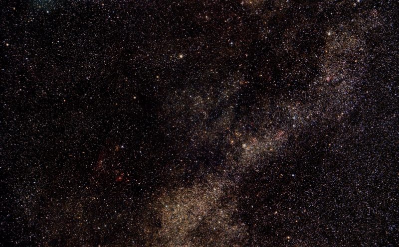 Band of reddish cloud of stars across star field.