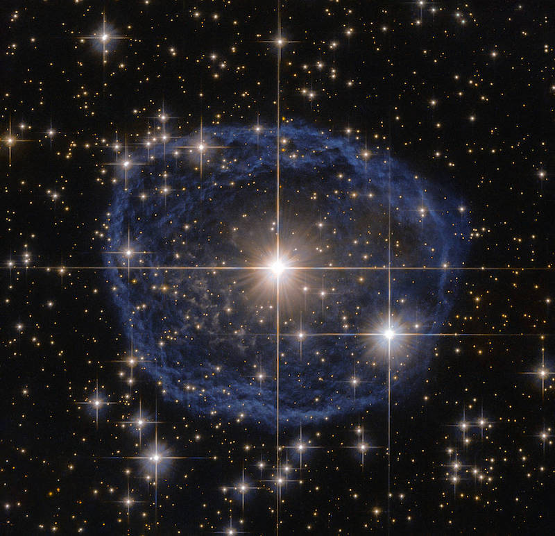 Starry background with bright star in center surrounded by a gaseous blue ring.