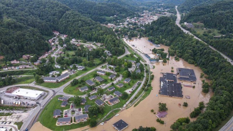 Kentucky flooding: Wide brown stream between green hills, with buildings and roads swamped.