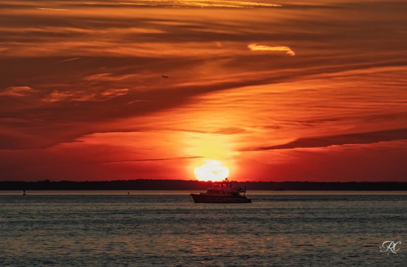 Earth farthest from the sun: Orange sunset over water, with a boat in the foreground.
