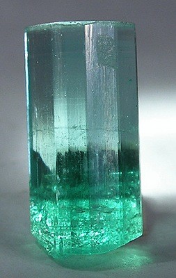 Columnar natural crystal, greener with inclusions at the bottom fading to near clear at the top.