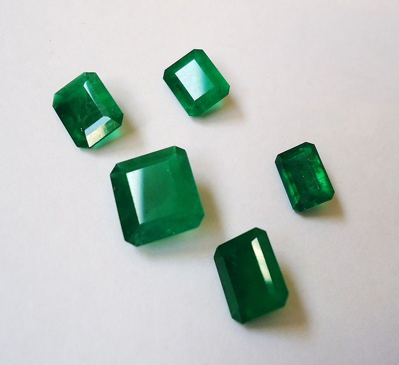 Five faceted emerald gemstones.