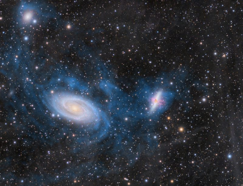 M81 and M82: A spiral galaxy and cigar-shaped galaxy with blue tendrils interacting.