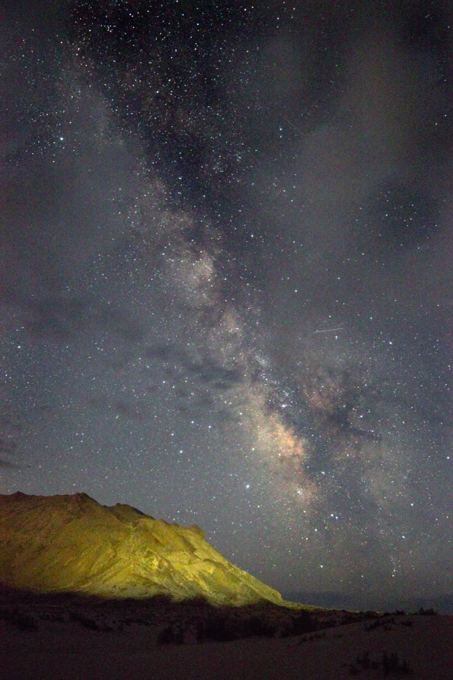 Rocky foreground with tall Milky Way behind.