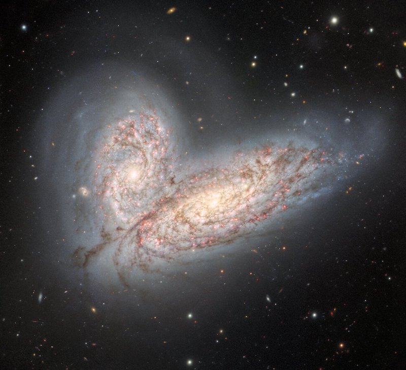 Galactic collision: Two spiral galaxies starting to merge, at angles with each other.
