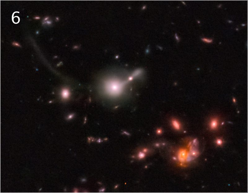 Small galaxies from white to red spatter the black background.