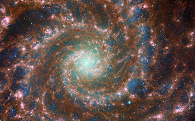 Spiral of multicolored light against a black background with blue and pink blotches and greenish center.