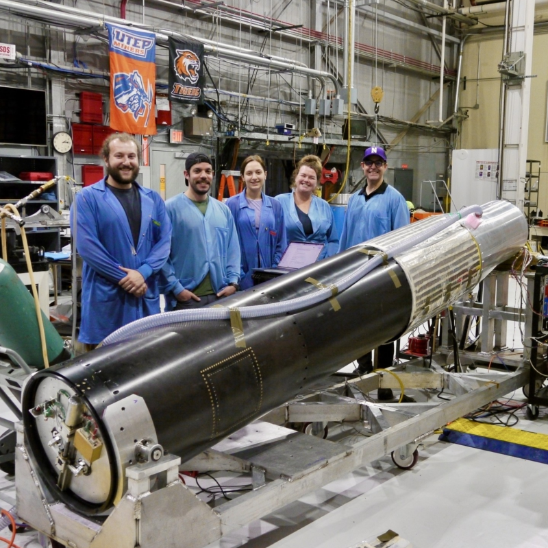 Scientists lined up behind a big rocket.