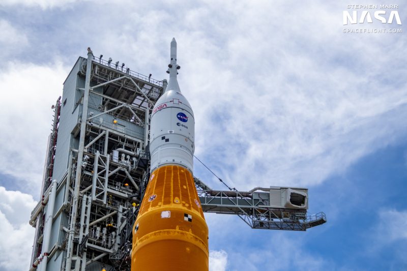 Partial shot of an orange booster, plus the white Orion space capsule on top.