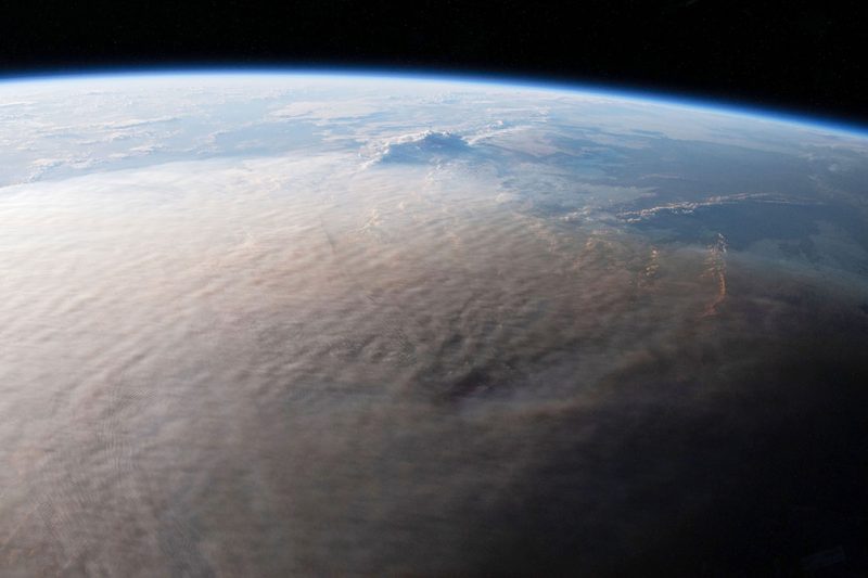 Part of Earth from above showing tan cloud enveloping most of the view.