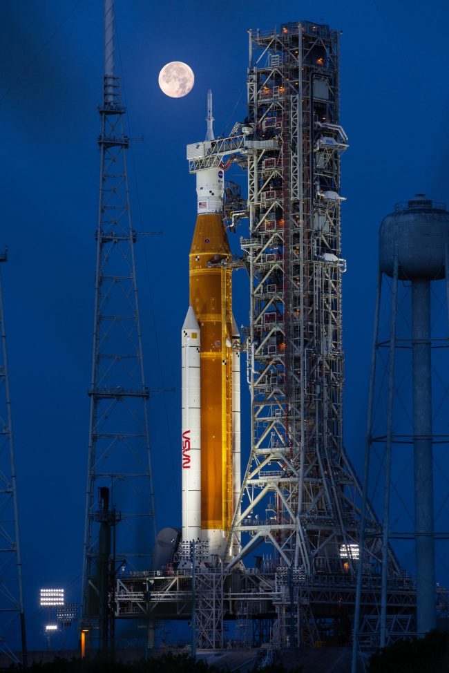 Rocket at launch gantry with a full moon on the background.