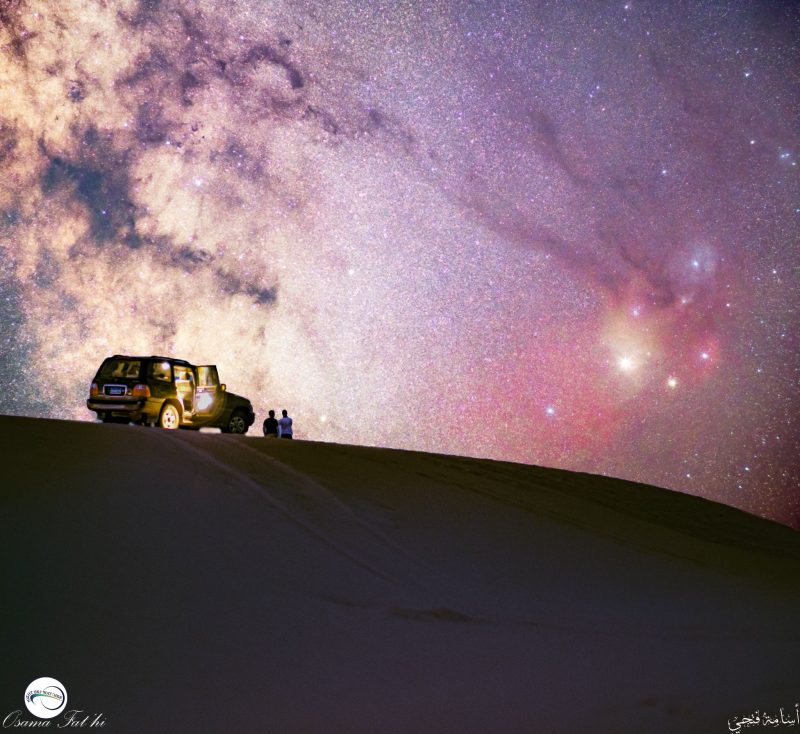Milky Way dark clouds with streamers stretching to colorful stars, truck in foreground.