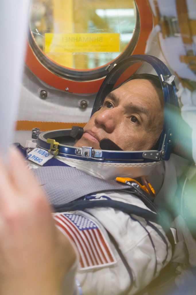 Launches: A man in a space suit looks through the window of a spacecraft.