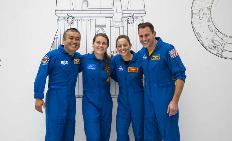 Two male and 2 female astronauts in blue jump suits, looking happy.