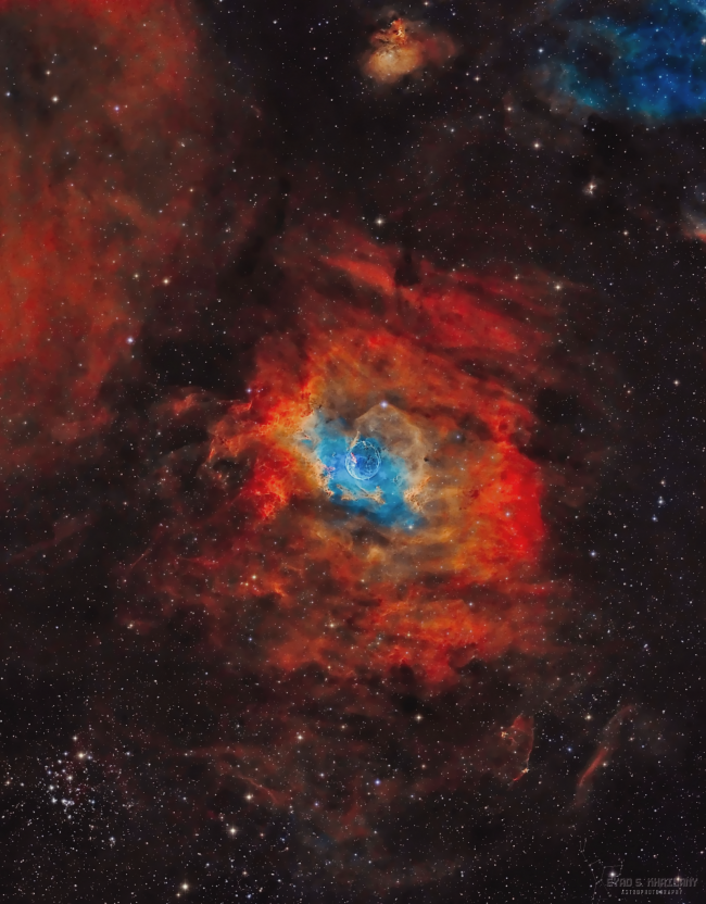 Almost circular red cloud in space with brilliant blue center, with scattered stars.