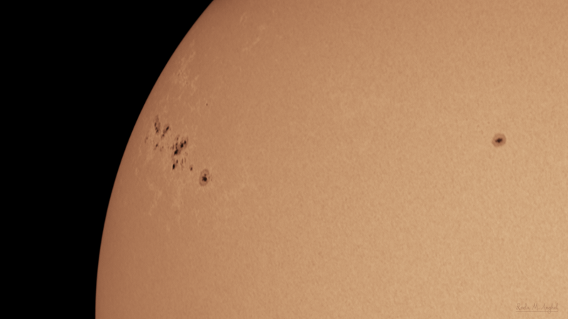 The sun, seen as a sectional yellow sphere with small dark spots.