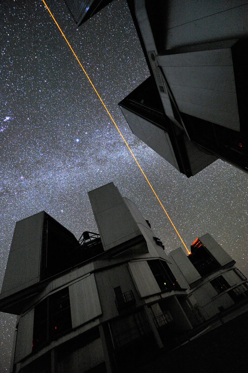 A laser shooting up from an observatory into a starry sky.