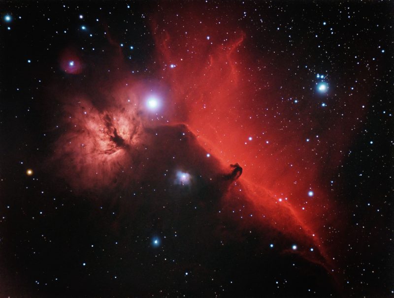 November deep sky: Large red cloud in space with a small horsehead-shaped dark indentation.