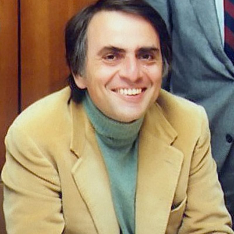 Smiling dark-haired man in light-colored jacket.